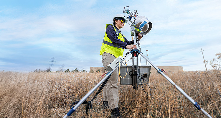A technician sets up a remote sensing monitoring device in a field