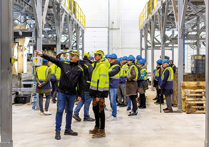 people in hard hats and high-visibility vests walking through a modern industrial facility
