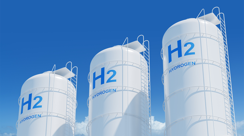 Three large white hydrogen storage tanks marked "H2" against a clear blue sky, representing hydrogen energy infrastructure and the growing hydrogen economy.