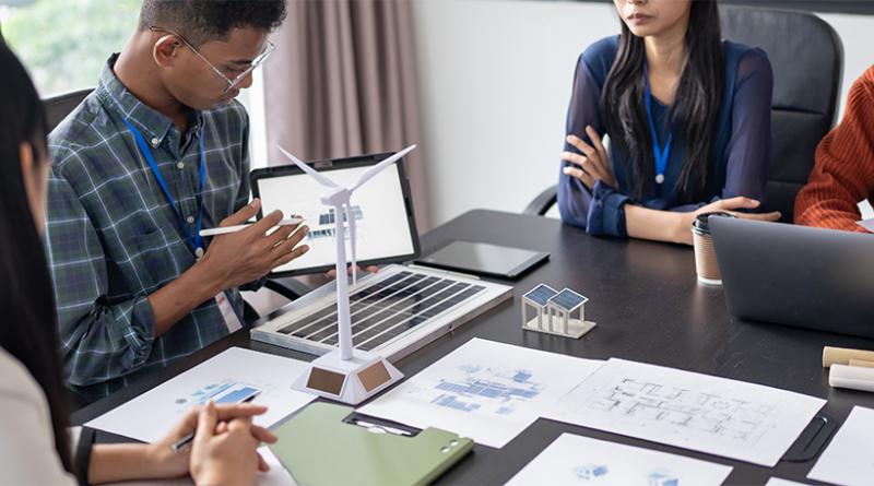 Clean energy startup team discussing wind and solar power projects around a conference table.