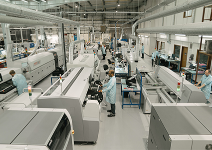 an electronics manufacturing floor equipped with surface-mount technology assembly lines and automated inspection machinery