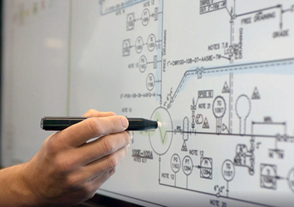 a person holding a pen and pointing at a technical drawing